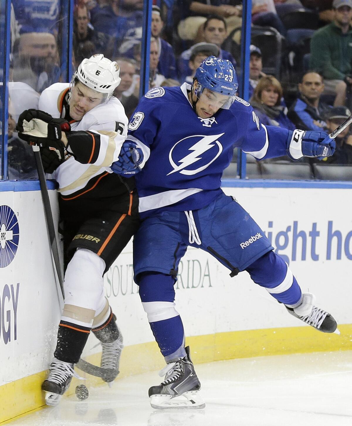 Ducks defenseman Ben Lovejoy, left, is checked into the boards by Tampa Bay Lightning right wing J.T. Brown during the second period of the Ducks' 5-1 loss Thursday.