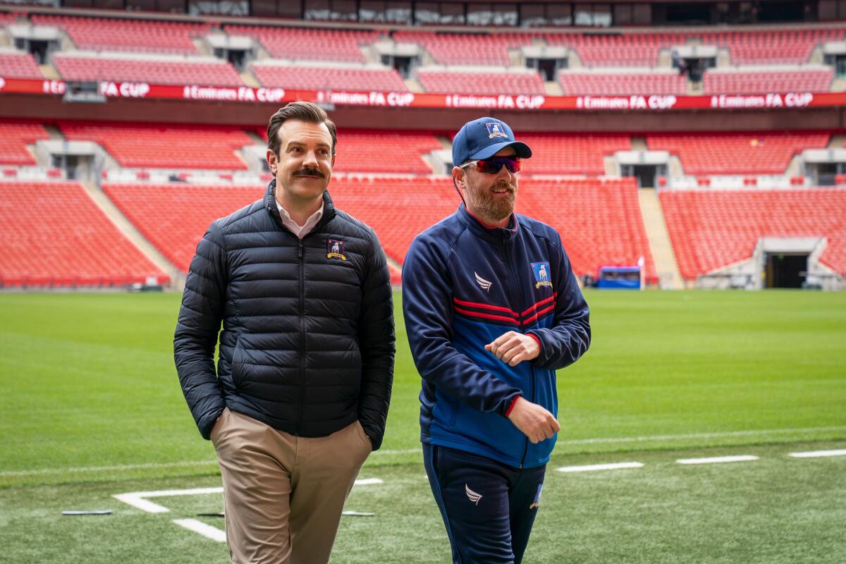 Two coaches in a soccer stadium.