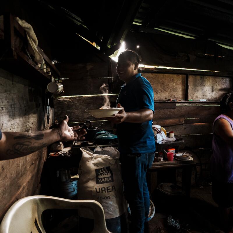 Ricardo García, left, with his cousin, center, at his parents' home, where slices of old volador poles serve as stools.