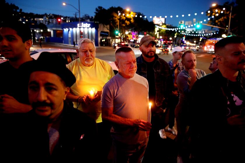 LOS ANGELES, CA - NOVEMBER 20: Dean Bright, center, of West Hollywood, attends a candlelight vigil along Santa Monica Blvd. in front of Rocco's on Sunday, Nov. 20, 2022 in Los Angeles, CA. "End the violence, we need strict gun control. This is not only an LGBTQ problem. We need to be brought together, not separated," said Bright. City leaders and community organizations hold a candlelight vigil in solidarity with the LGBTQ community of Colorado Springs, Colorado, where at least five people were shot to death at a nightclub late Saturday. (Gary Coronado / Los Angeles Times)