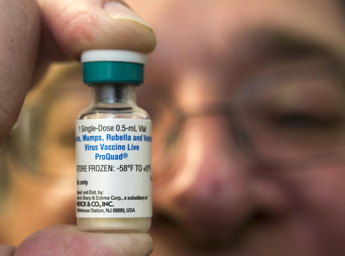 A pediatrician holds a dose of the measles, mumps and rubella vaccine.