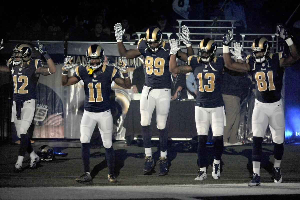 To acknowledge the events in Ferguson, Mo., members of the St. Louis Rams raise their hands as they walk onto the field before playing the Oakland Raiders in St. Louis.
