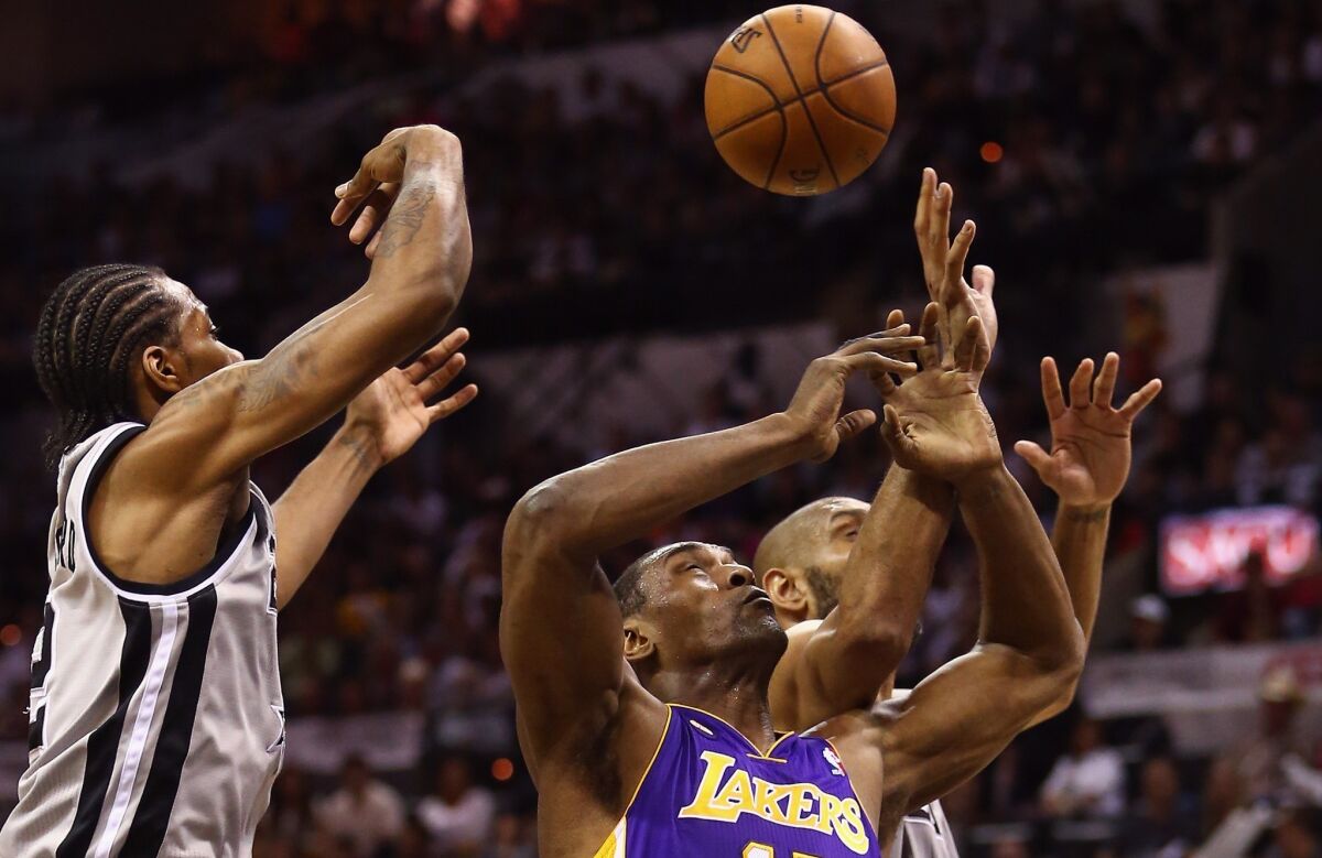 Lakers forward Metta World Peace battles Spurs forward Kawhi Leonard and power forward Tim Duncan (background) for a rebound in the first half Sunday afternoon.