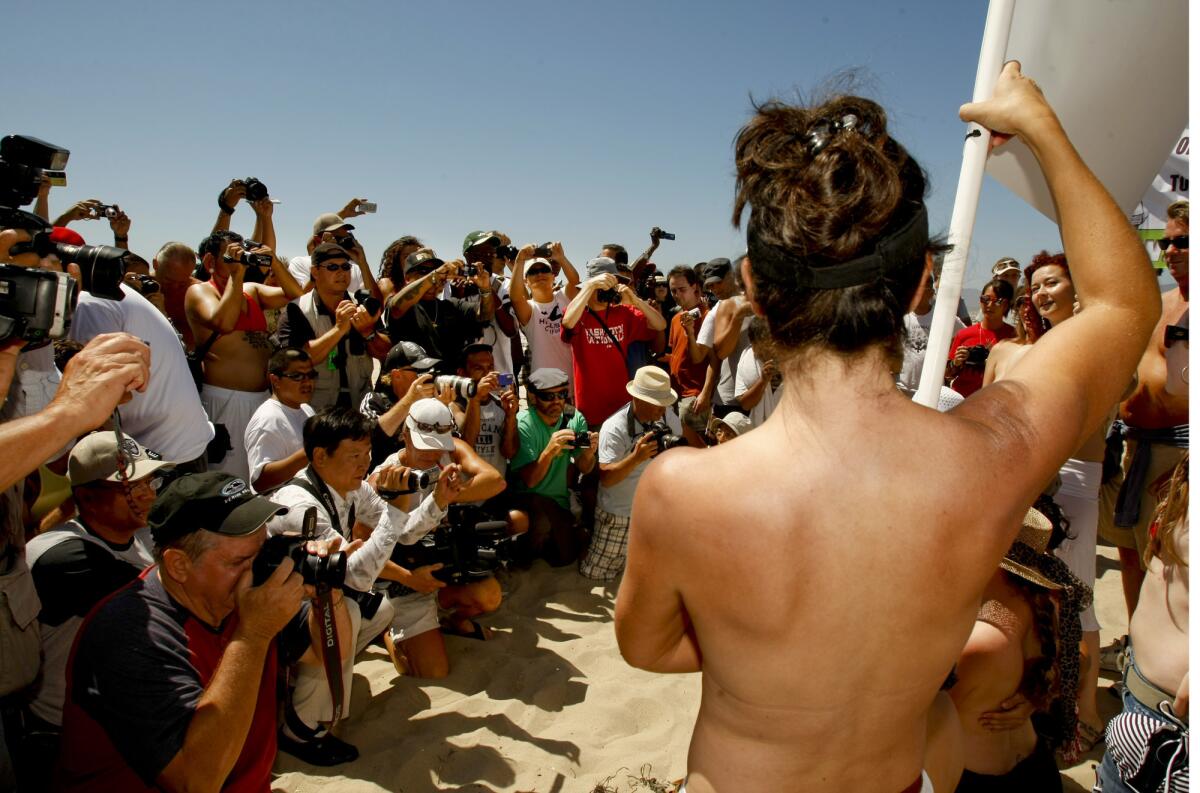 Photographers shoot photos as topless protesters march down the Venice Beach boardwalk in August 2010.