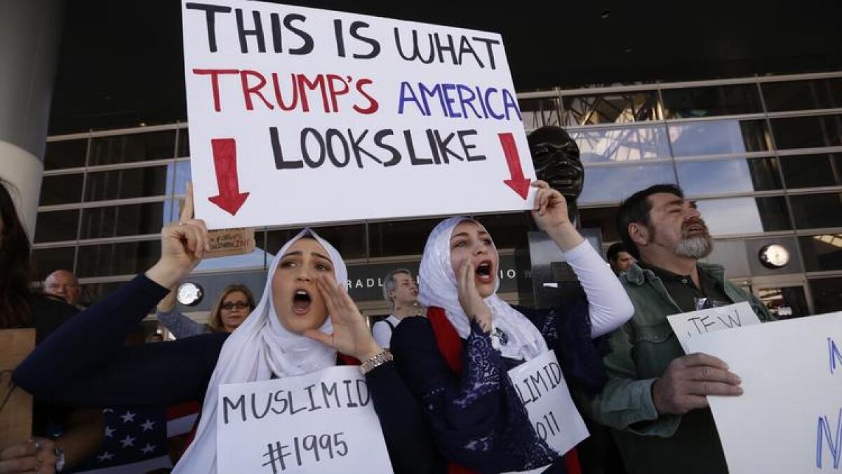 Noor Hindi, left, and Shah Najjar, middle, join the protest at the Tom Bradley International Terminal at Los Angeles International Airport on Monday.
