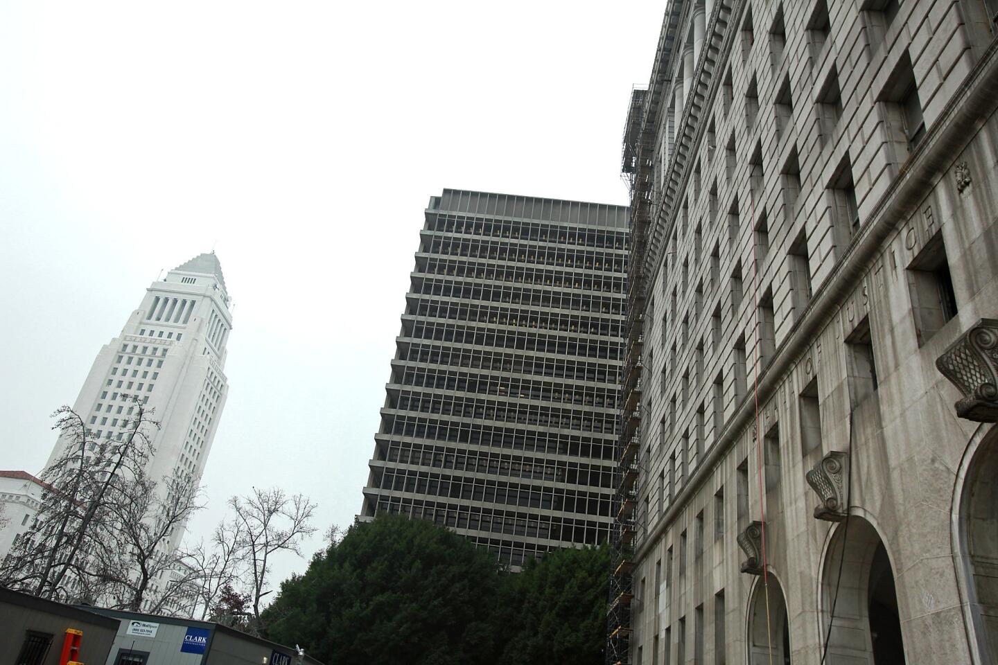 The facade of the County Hall of Justice, right, is dark and dirty compared with that of Los Angeles City Hall, left. The material of both buildings is Sierra white granite, quarried near Fresno. The exterior of the Hall of Justice will soon be cleaned and restored.