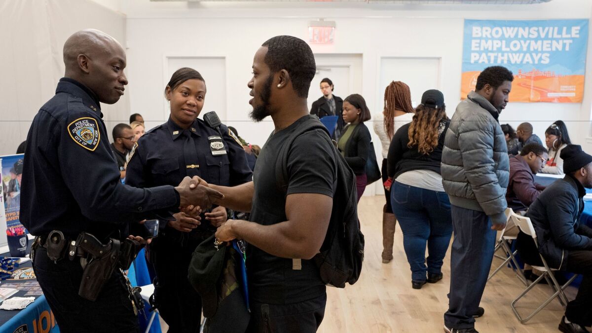 Tevin Green, center, shakes hands with New York Police Department recruiter Officer Omisanya during a job fair on Nov. 15, 2016, in Brooklyn.