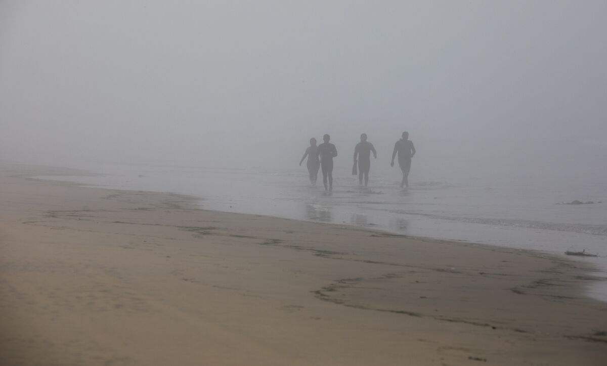 Migrants walk and run along the beach at Borderfield State Park after swimming across from Tijuana.