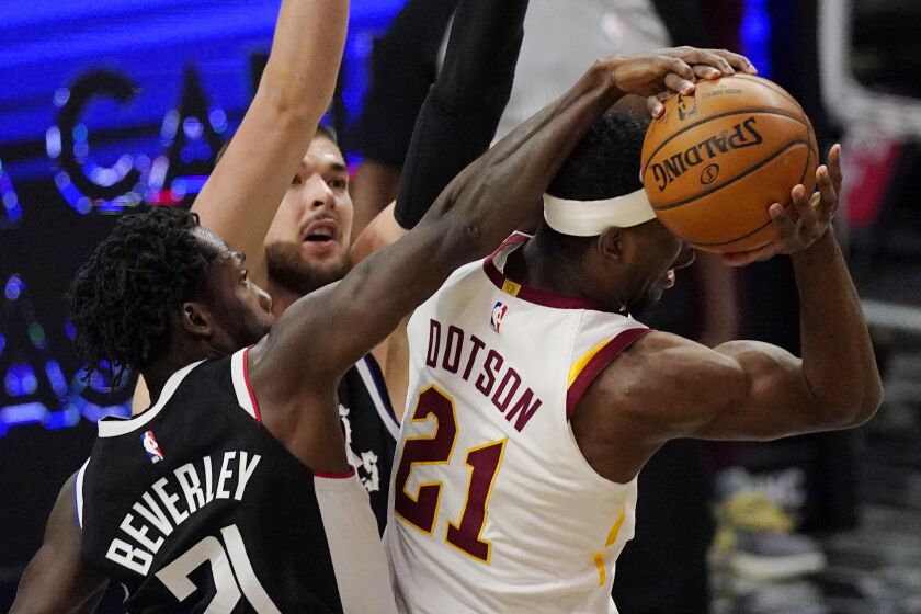 Cleveland Cavaliers guard Damyean Dotson, right, has his shot blocked by Los Angeles Clippers guard Patrick Beverley, left, as center Ivica Zubac defends during the second half of an NBA basketball game Sunday, Feb. 14, 2021, in Los Angeles. The Clippers won 128-111. (AP Photo/Mark J. Terrill)