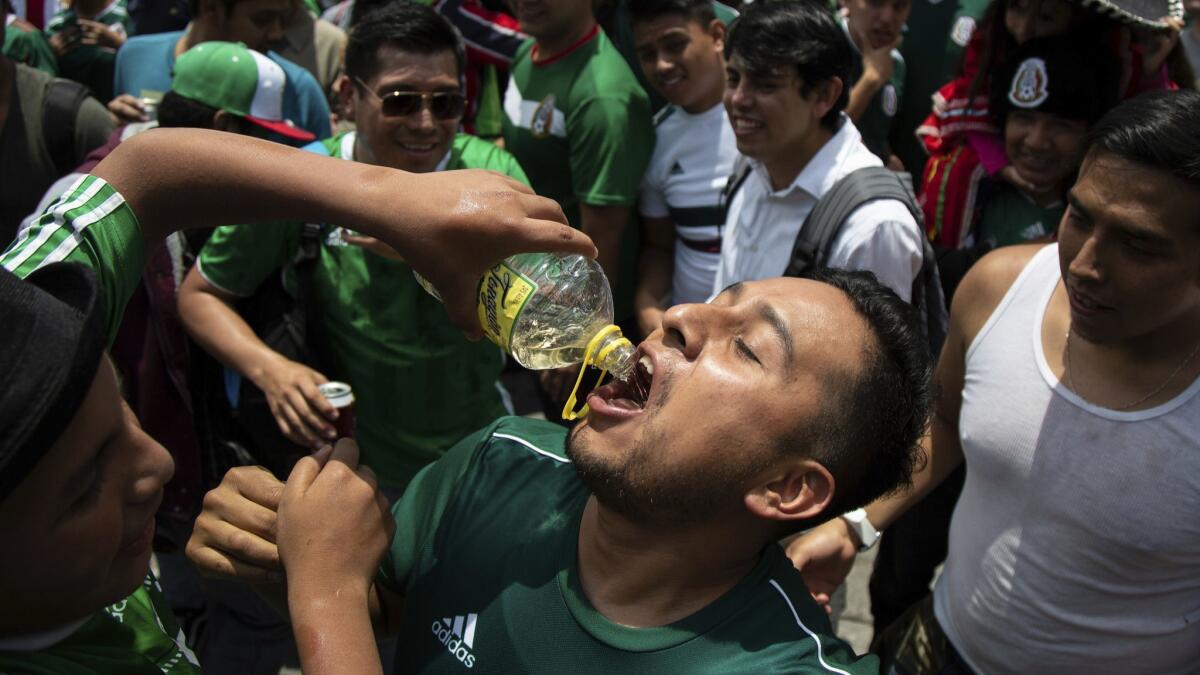 A fan has tequila poured down his throat during the celebration of Mexico's 2018 World Cup win over Germany at the Angel of Independence in Mexico City.