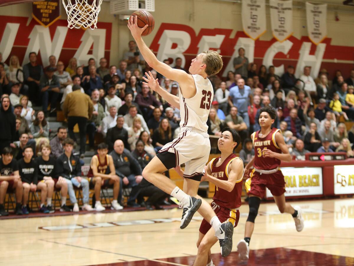 Laguna Beach's Brooks Hogenauer (23) makes an easy layup after a steal off Ocean View’s Cash Schnekenburger, who trails the play in the first round of the CIF Southern Section Division 3AA playoffs on Wednesday.
