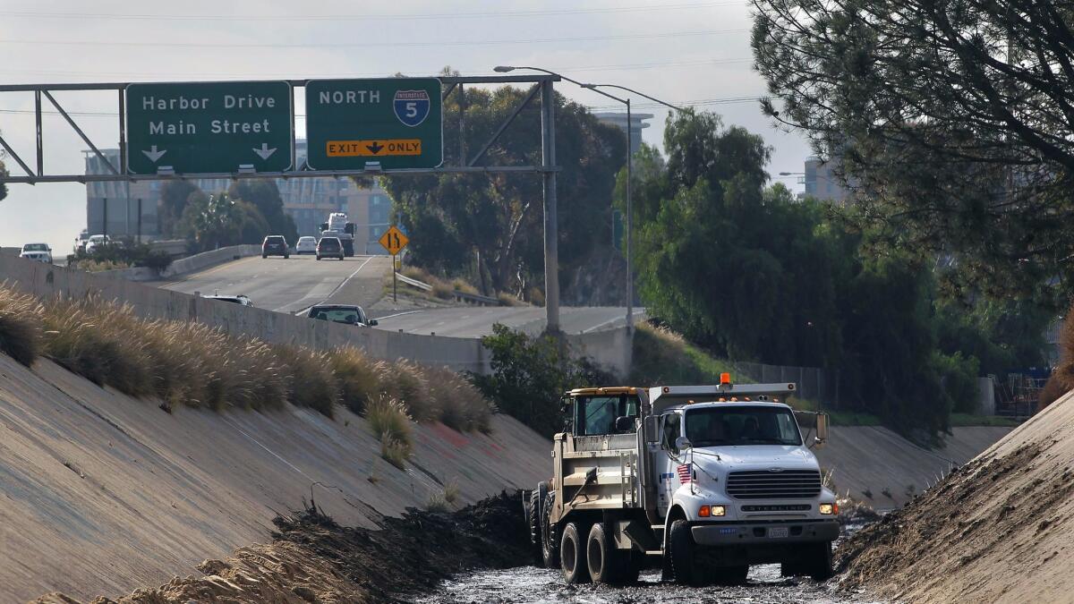 Workers using 10-wheel trucks and heavy equipment in 2016 between Interstate 5 and Interstate 15 where Chollas Creek is lined with concrete.| John Gastaldo / San Diego Union-Tribune