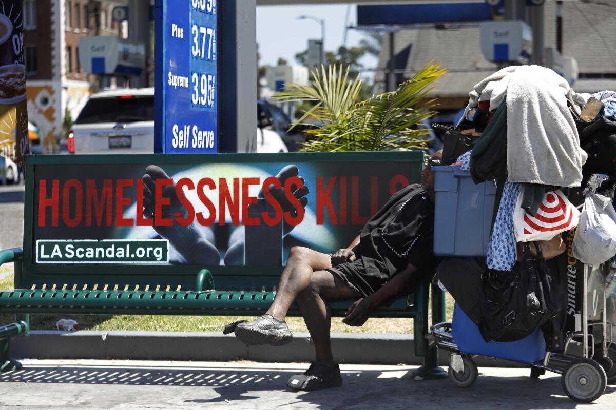 A man rests next to his belongings on a bus bench in Los Angeles in 2019. 