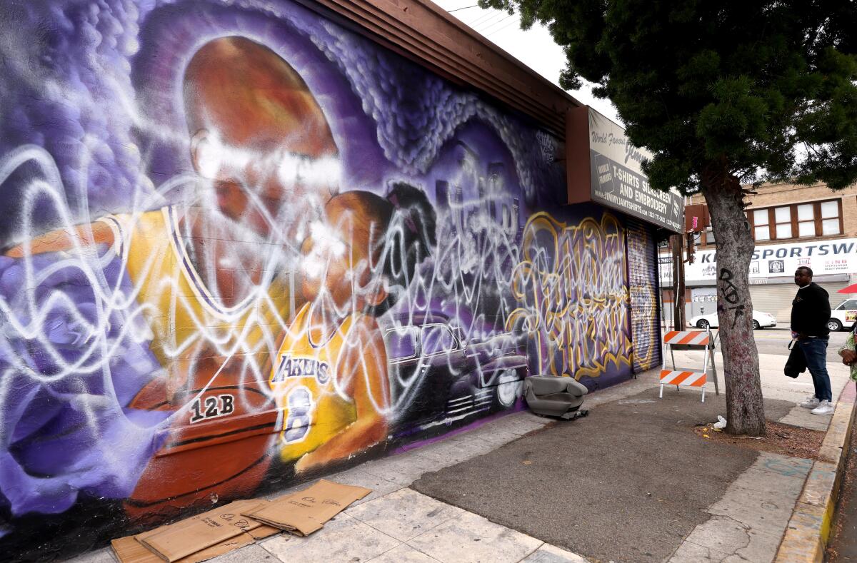 James Ewing, co-owner of Jimmy Jam T-Shirts, looks at a mural of Kobe and Gianna Bryant that has been vandalized again.