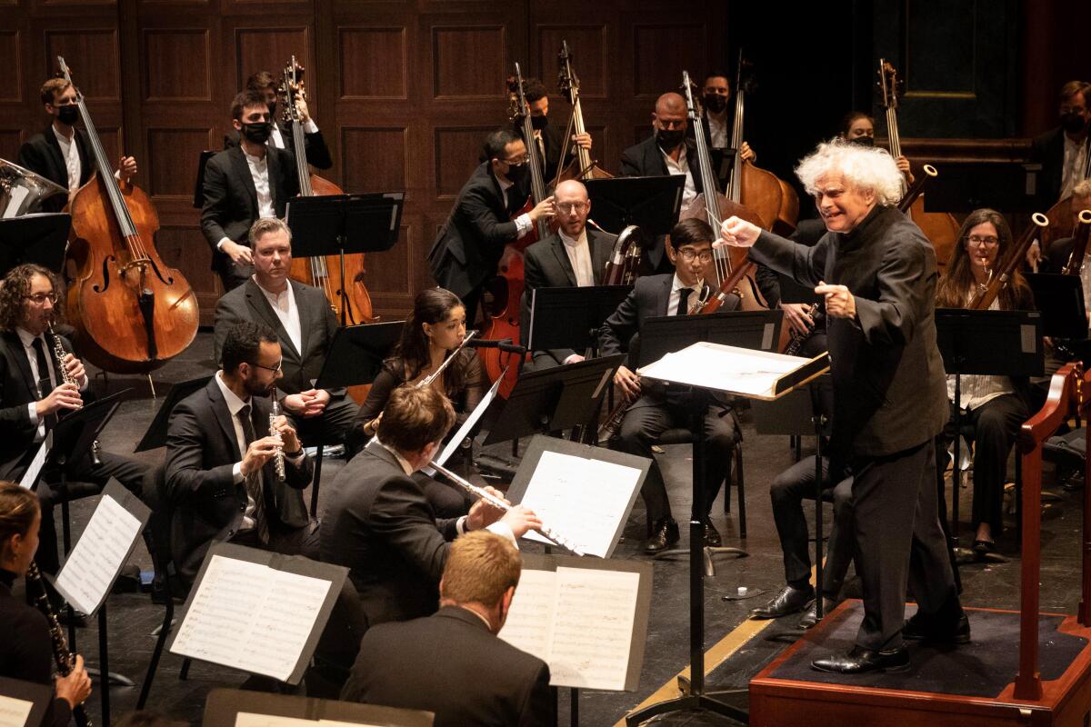 A man with gray hair conducts an orchestra 