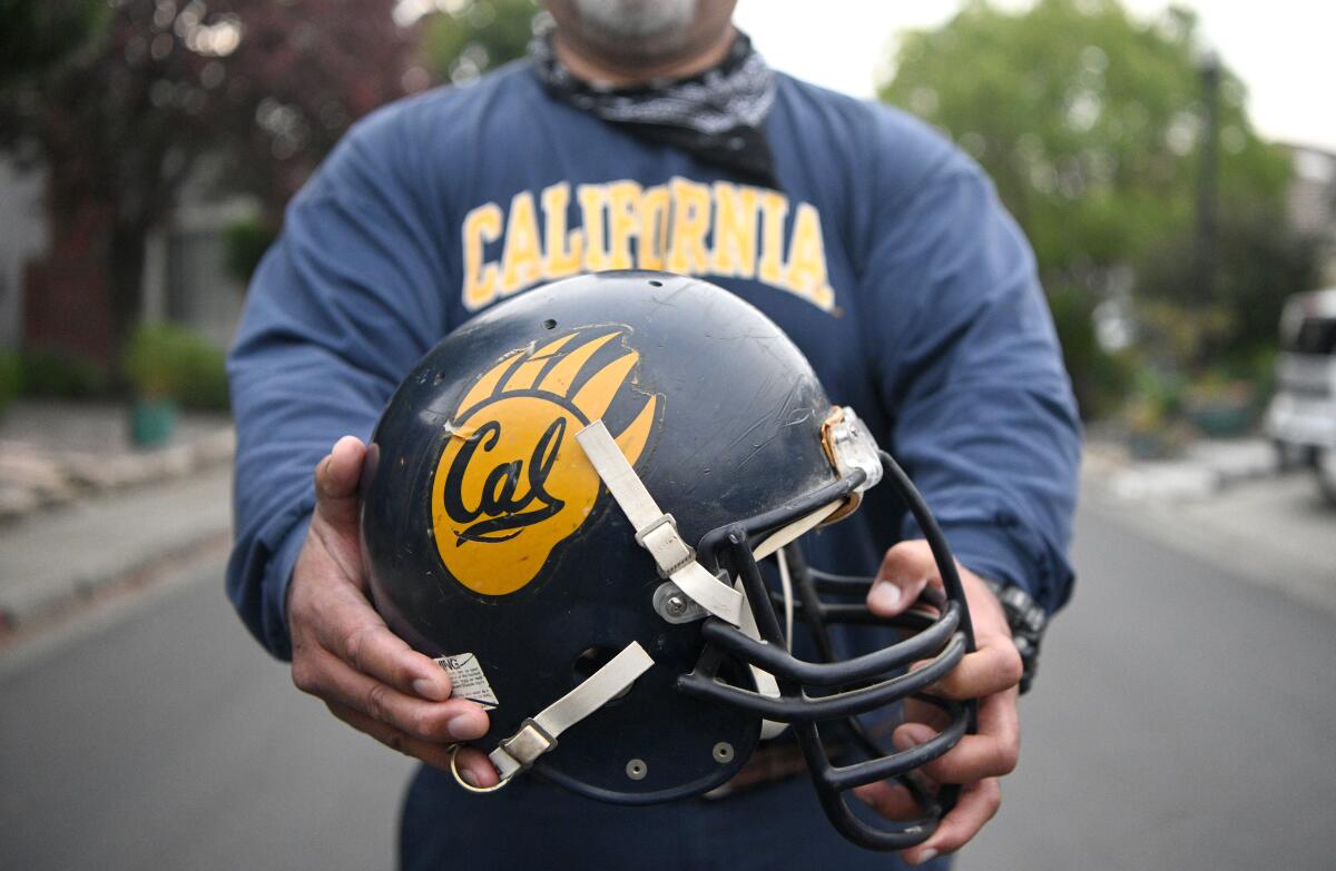 Former Cal player George Niualiku holds his old helmet. 