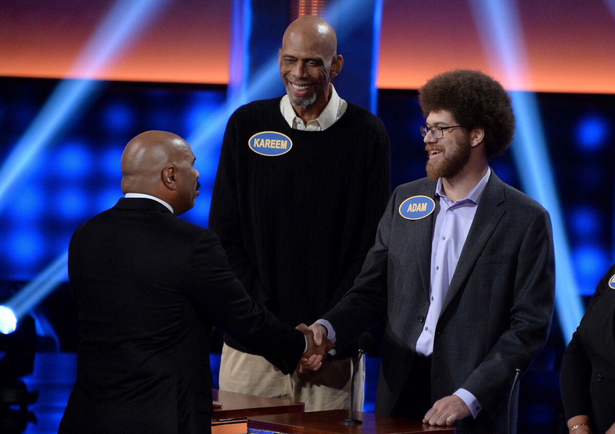 Adam Abdul-Jabbar, right, shakes hand with "Family Feud" host Steve Harvey, center, as Kareem Abdul-Jabbar looks on.