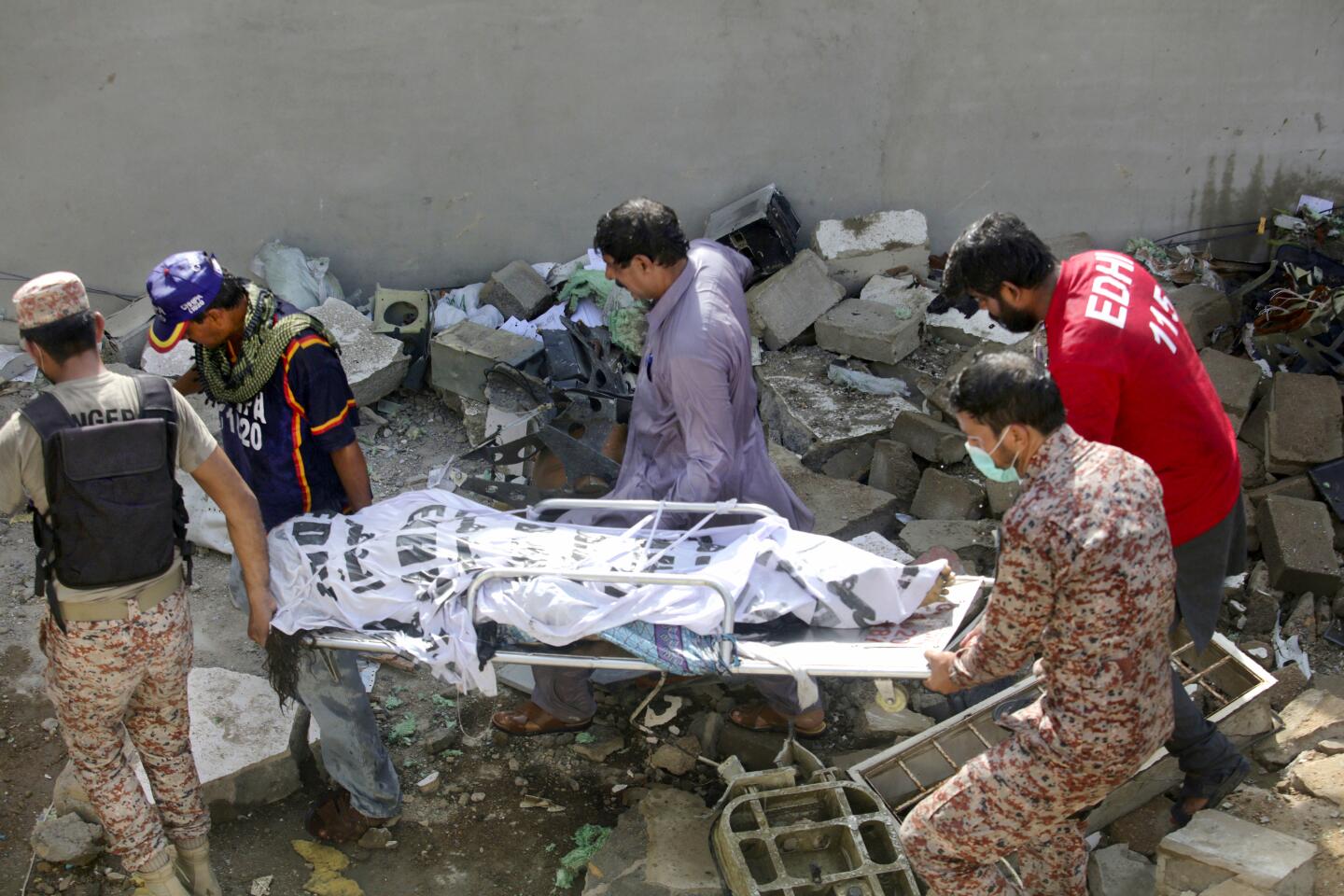 A victim's body is removed from the wreckage of a Pakistani airliner that crashed Friday in a neighborhood in Karachi.