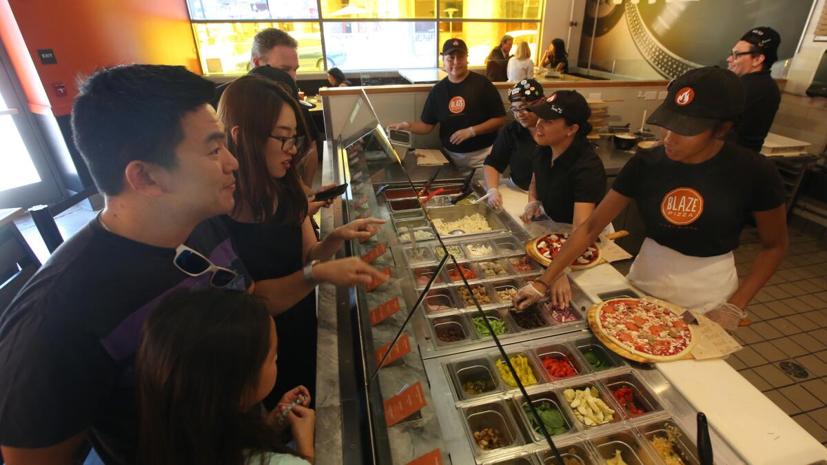 Customers watch as their pizza is being prepared as customers watch at Blaze Pizza in Pasadena on July 19. Blaze Pizza is a fast-casual pizza chain with national ambitions.