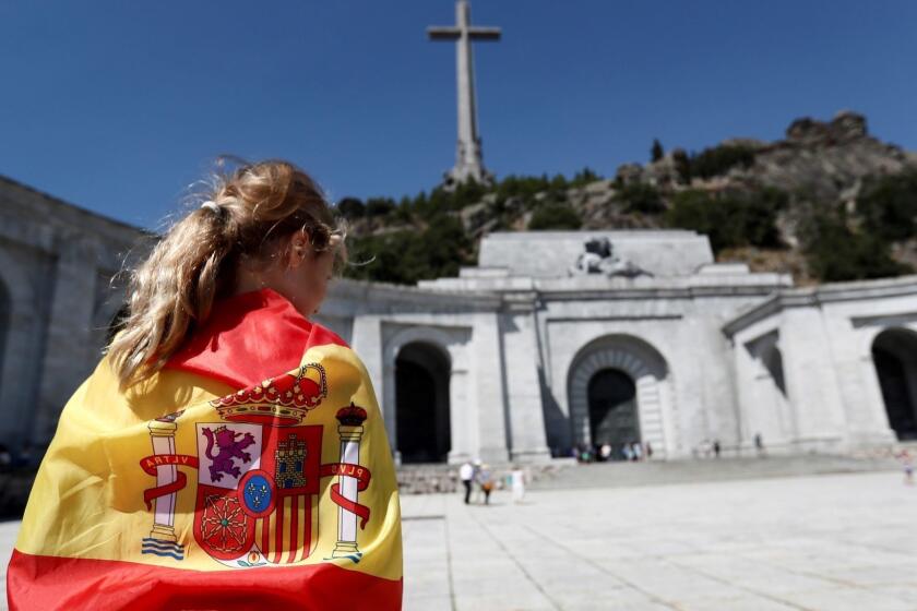 Mandatory Credit: Photo by MARISCAL/EPA-EFE/REX/Shutterstock (9796125d) A woman is wrapped in a Spanish national flag on the esplanade of the El Valle de los Caidos (The Valley of the Fallen) memorial complex in the town of San Lorenzo del Escorial, 40 kilometers from Madrid, Spain, 21 August 2018. The new Spanish socialist government is to pass a decree on 24 August to modify the Spanish Historic Memory Law to enable the exhumation and removal of late Spanish fascist dictator Francisco Franco's body from the complex in a move to make it a place of remembrance of the civil war instead of a site for the gloryfication of Franco's dictatorship. The El Valle de los Caidos is a controversial complex which was erected under Franco's rule - partially by forced laborers and political prisoners - to bury the tens of thousands Spanish soldiers from both sides fallen during the Spanish Civil War. Dictator Franco ruled Spain from 1939 to his death in 1975. Spanish Government to pass decree to exhume body of dictator Franco, San Lorenzo De Escorial, Spain - 21 Aug 2018 ** Usable by LA, CT and MoD ONLY **