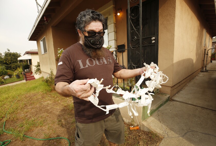 Joe Gonzalez, who lives in Boyle Heights near the Exide plant, holds patient wrist bands accrued during his cancer treatment