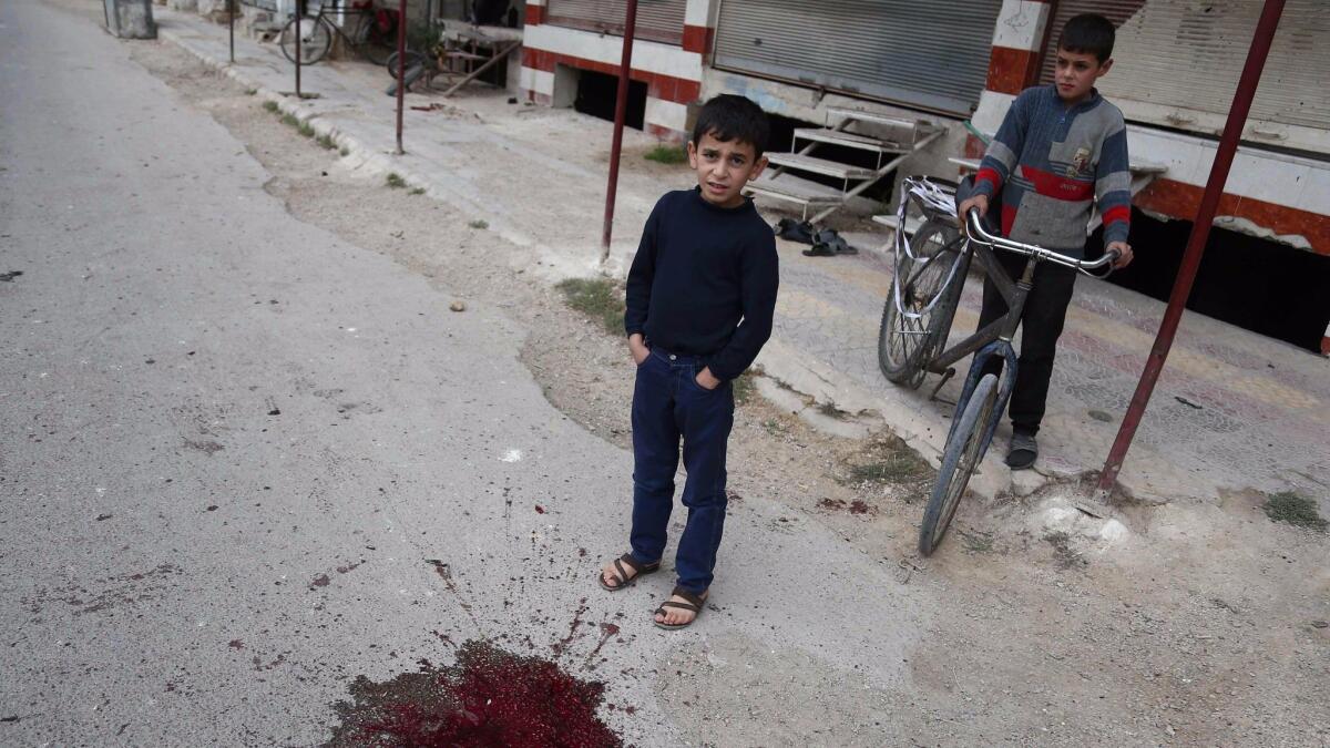 Syrian children stand at the bloodstained site of a shelling Oct. 31 that killed schoolchildren in the rebel-held town of Jisreen, east of the capital, Damascus.