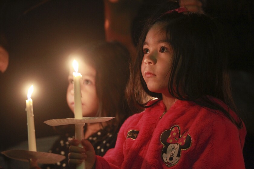 A pair of young girls hold candles during a candlelight vigil.