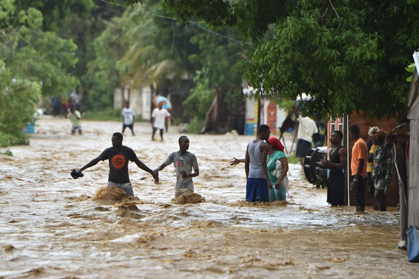 People try to cross the overflowing Rouyonne river in the community of Leogane, south of Port-au-Prince, Haiti, on Oct. 5, 2016.