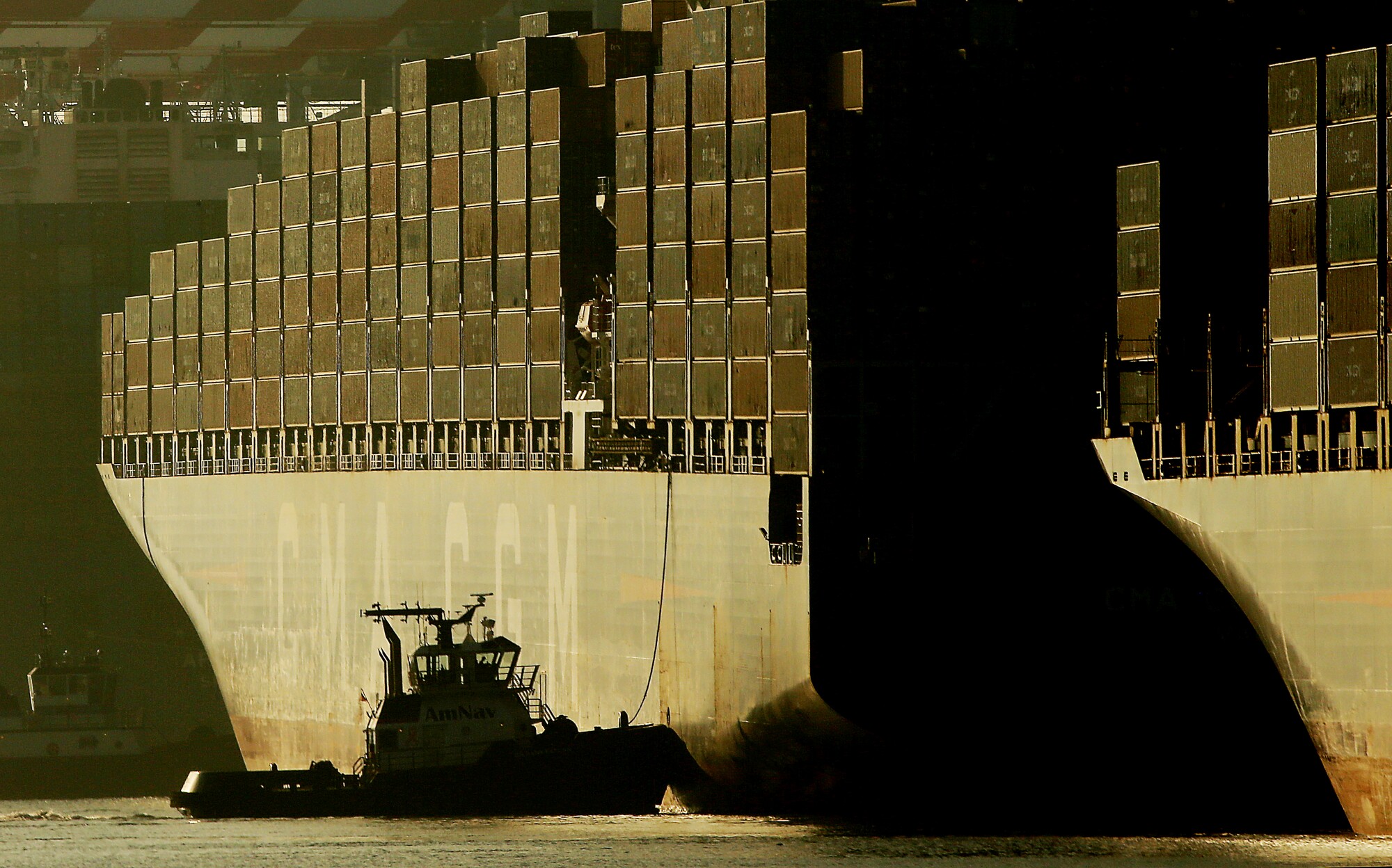 Tugboats guide a container ship to a dock at the Port of Los Angeles