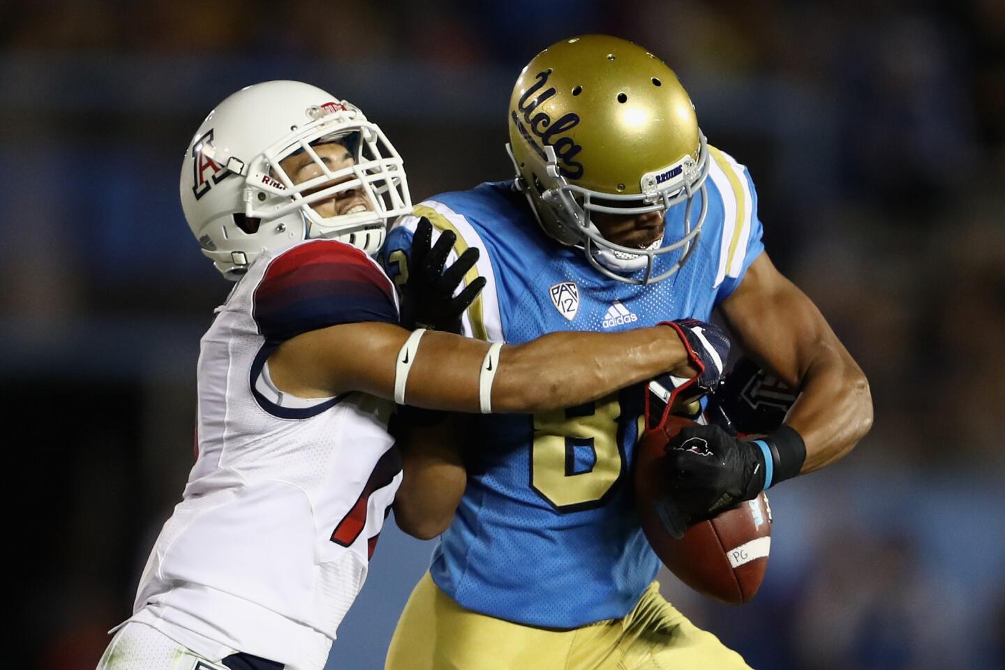 Arizona defensive back Jace Whittaker strips the ball from UCLA receiver Eldridge Massington during the first half.