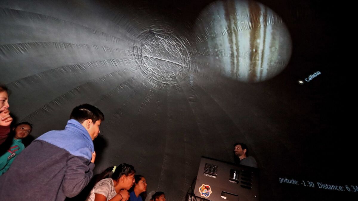 Students view an image of Jupiter projected in an inflatable mobile planetarium at an Oak View Elementary School assembly Friday in Huntington Beach.