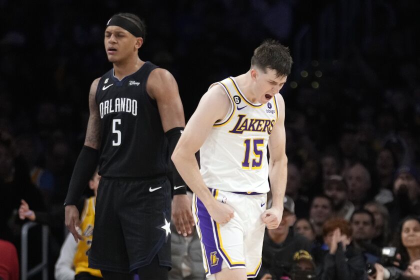 Los Angeles Lakers guard Austin Reaves (15) reacts after scoring next to Orlando Magic forward Paolo Banchero (5) during the second half of an NBA basketball game Sunday, March 19, 2023, in Los Angeles. (AP Photo/Marcio Jose Sanchez)