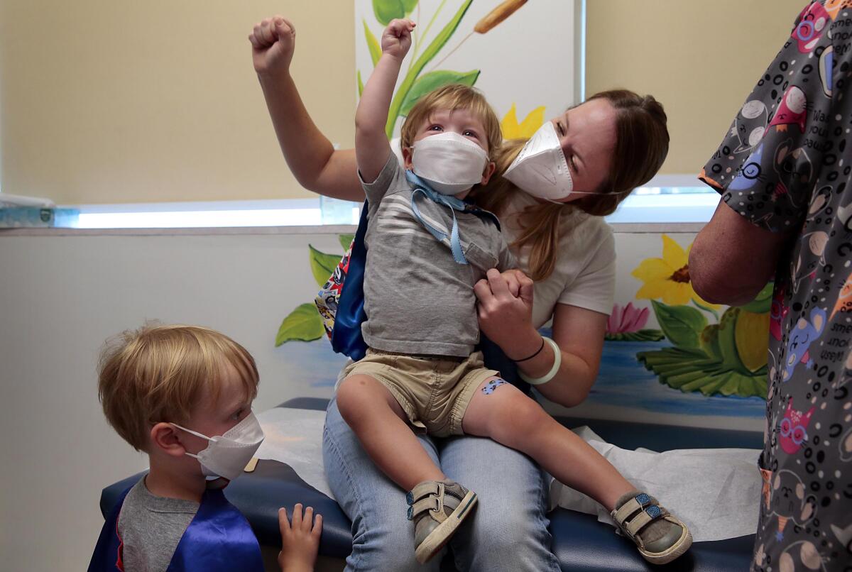 A young boy sits on his mother's lap. They both raise their arms.