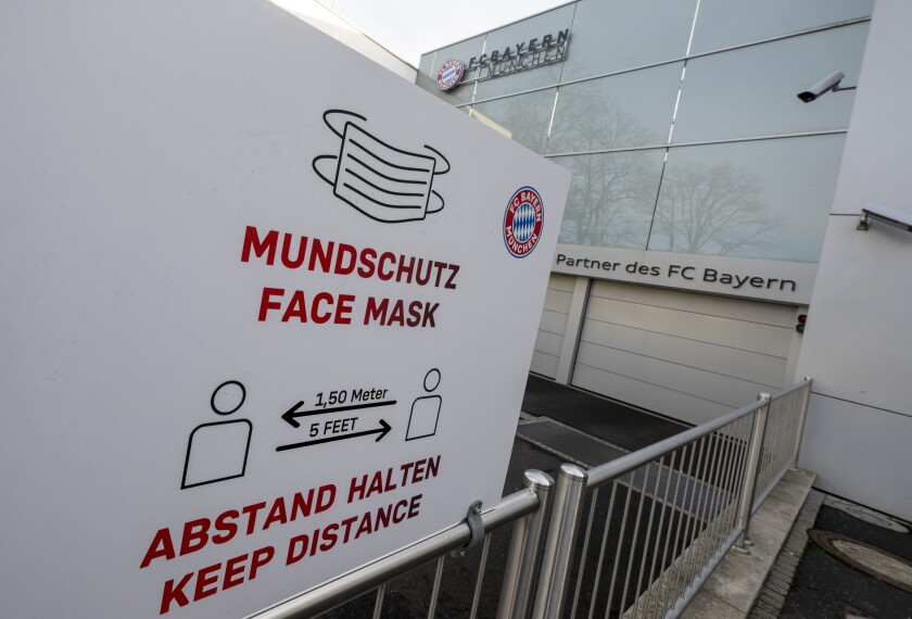 The logo of FC Bayern Munich and the notice about mouth protection and distance rules due to the Corona pandemic can be seen on a sign at the main building of the football club in Munich, Germany, Sunday, Jan. 2, 2022. The German league resumes in a depleted state on Friday, when defending champion Bayern Munich will struggle to field a competitive 11 against Borussia Moenchengladbach. Captain Manuel Neuer, Lucas Hernandez, Kingsley Coman, Corentin Tolisso, Alphonso Davies, Leroy Sane, Dayot Upamecano, Omar Richards and Tanguy Nianzou are on Bayern’s infected list. (Peter Kneffel/dpa via AP)