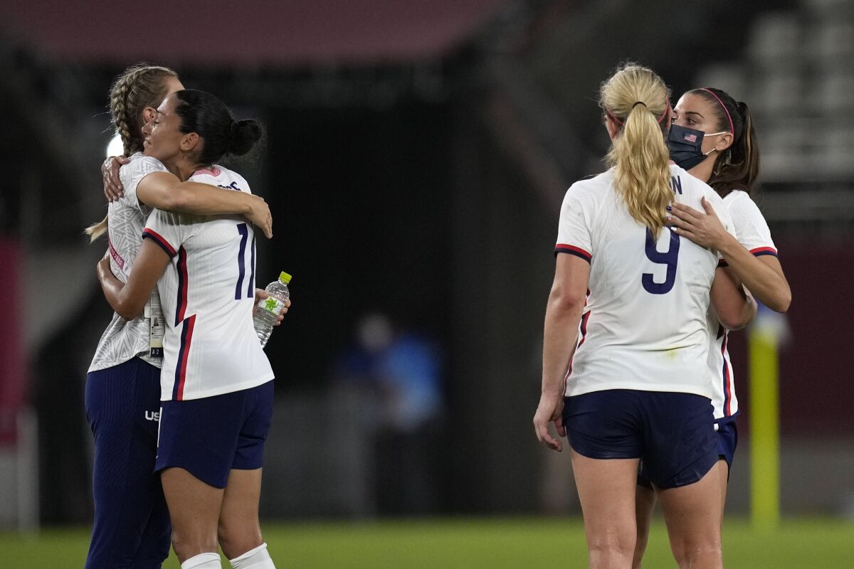United States players embrace after being defeated 1-0 by Canada during a women's semifinal soccer match at the 2020 Summer Olympics, Monday, Aug. 2, 2021, in Kashima, Japan. (AP Photo/Andre Penner)
