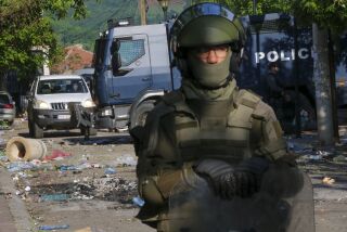 Soldados de KFOR, delante, y policías de Kosovo protegen un edificio municipal tras los choques del día anterior entre personas de etnia serbias y tropas de la fuerza de paz de la OTAN KFOR en la localidad de Zvecan, en el norte de Kosovo, el martes 30 de mayo de 2023. (AP Foto/Dejan Simicevic)
