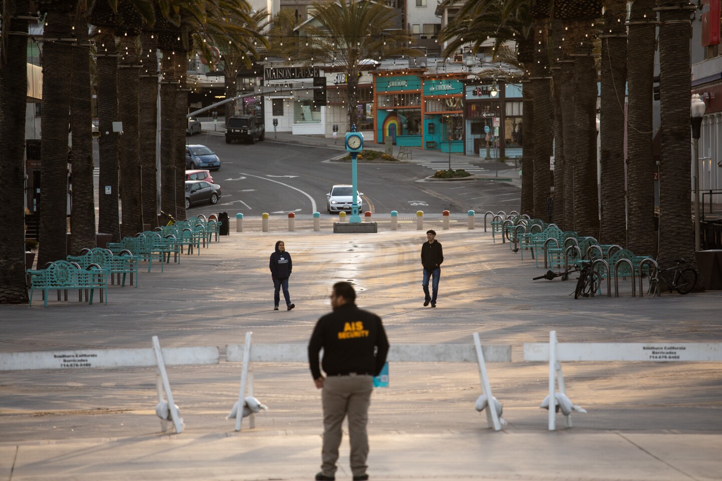 HERMOSA BEACH, CA --MARCH 28, 2020 - Marcos Ayala, center, from east Los Angeles, with Absolute Intl. Security, provides security for the Hermosa Beach Police Department in closing off The Strand and two-mile stretch of Hermosa Beach, CA, in an effort to prevent crowds and gatherings of people in the south bay town and slow the spread of the coronavirus, March 28, 2020. What began as only a city of Hermosa Beach, beach closure, quickly became a Los Angeles County beaches closure by late morning on Friday March 27, 2020, in an effort to slow the spread of the coronavirus. (Jay L. Clendenin / Los Angeles Times)