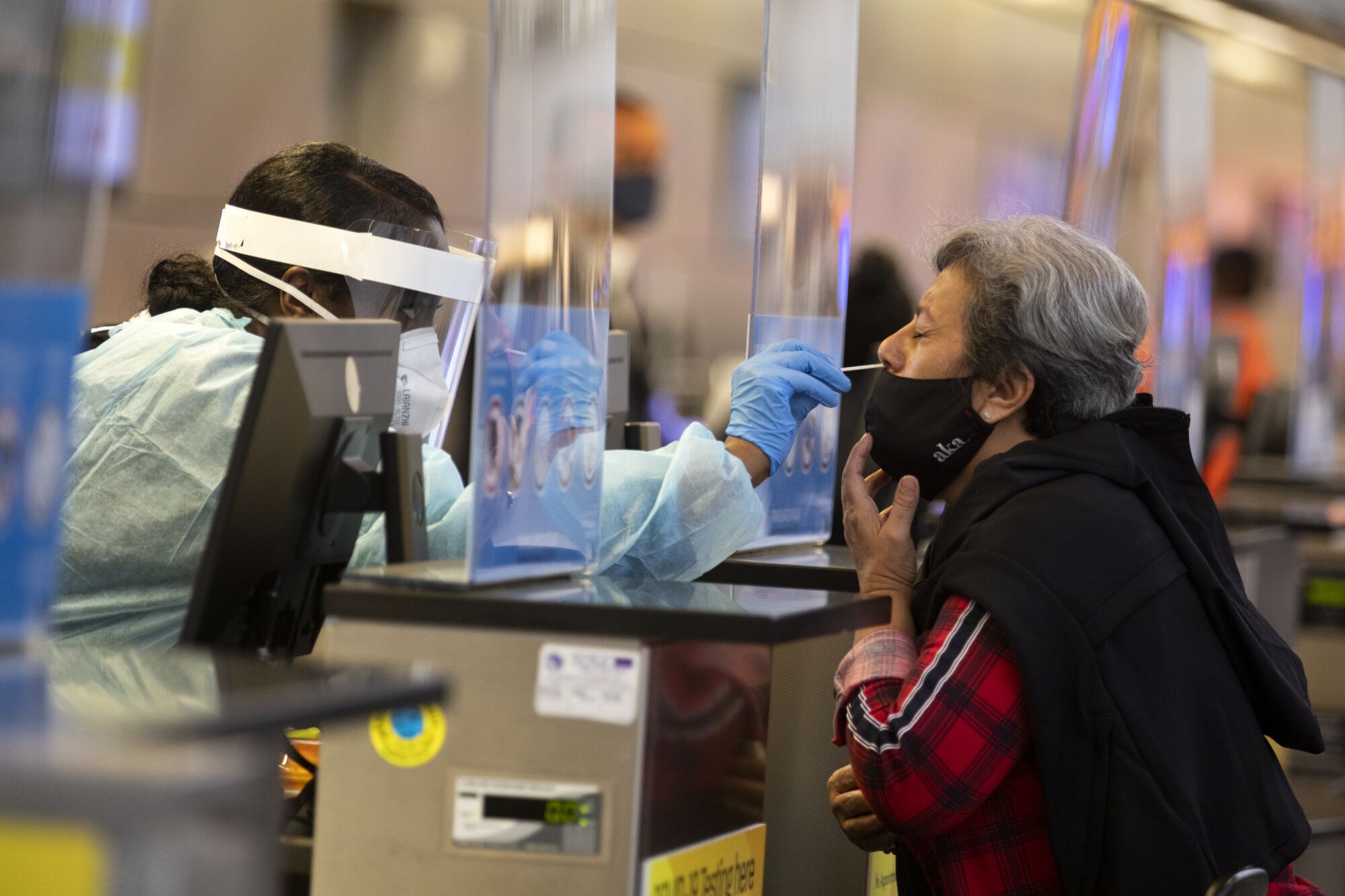 A health worker uses a nasal swab to administer a coronavirus on a traveler at LAX.