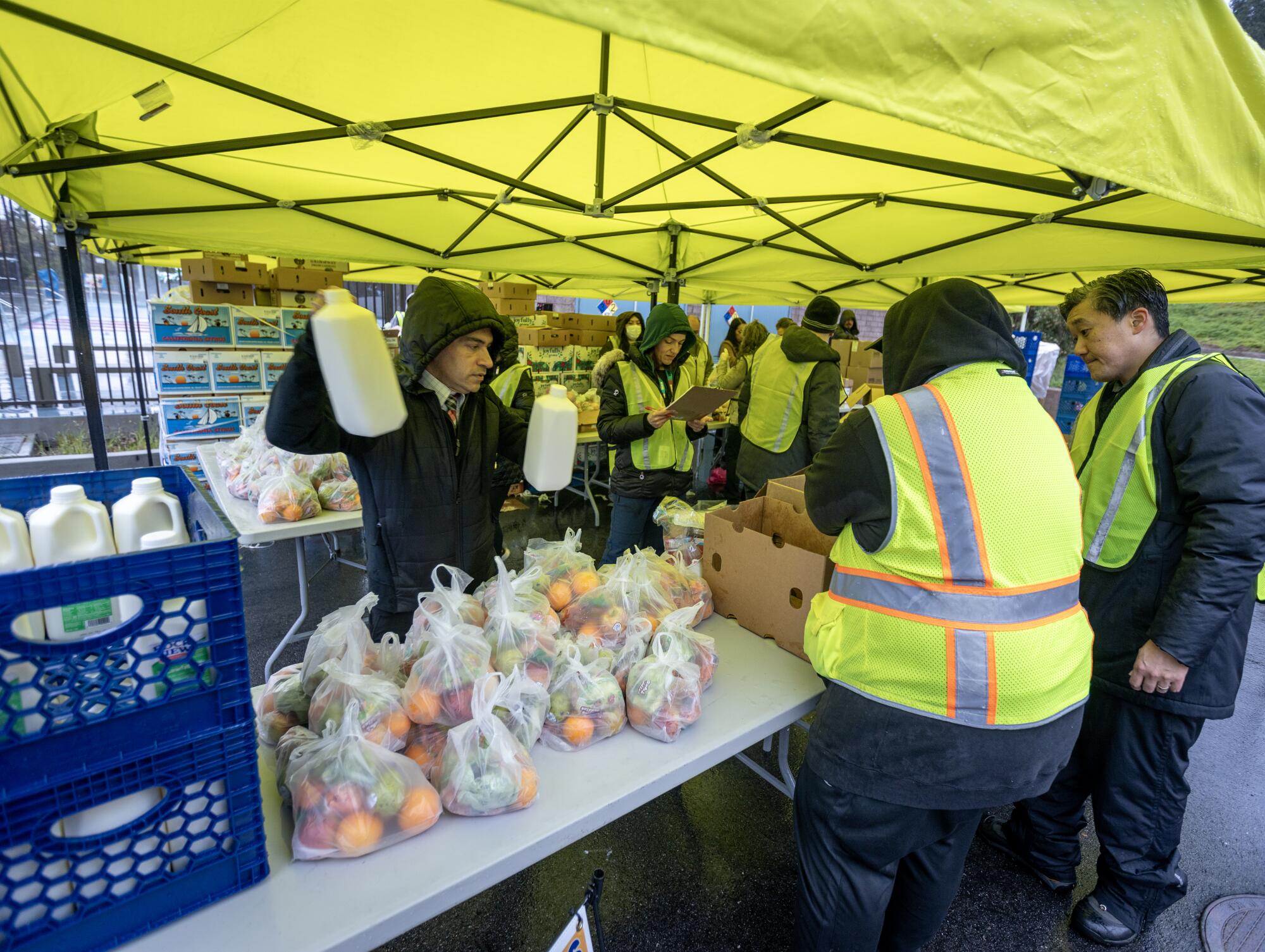 Workers distribute meals for students at an LAUSD grab & go site at the Lincoln Park Recreation Center in Los Angeles.