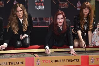 Lisa Marie Presley, left, Priscilla Presley and Riley Keough write their names in cement during a hand and footprint ceremony