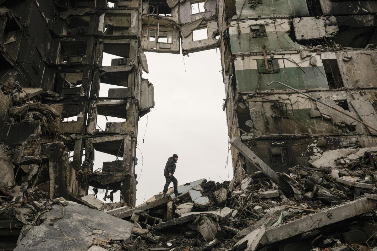 A person walks on the site of an apartment building destroyed during fighting. 