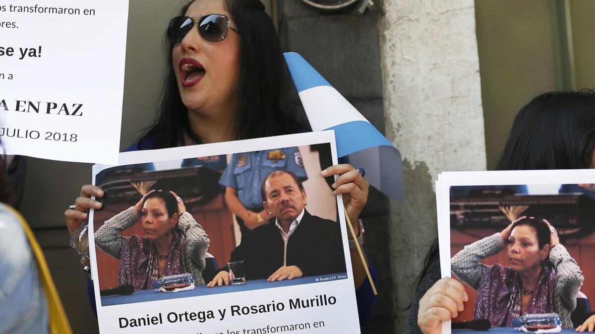 A protester holds a photo of Nicaraguan President Daniel Ortega and his wife, Vice President Rosario Murillo, during a rally outside Nicaragua's embassy in Mexico City, Thursday marked the 39th anniversary of the revolution against Anastasio Somoza.