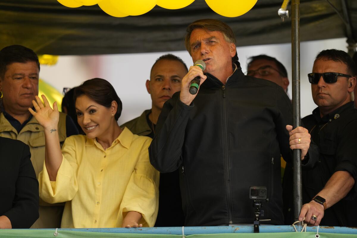 Brazilian President Jair Bolsonaro speaks as his wife Michelle waves