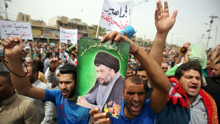 A supporter of Muqtada Sadr holds a portrait of the Shiite cleric during a protest against corruption in Baghdad's Sadr City neighborhood on May 6, 2016.
