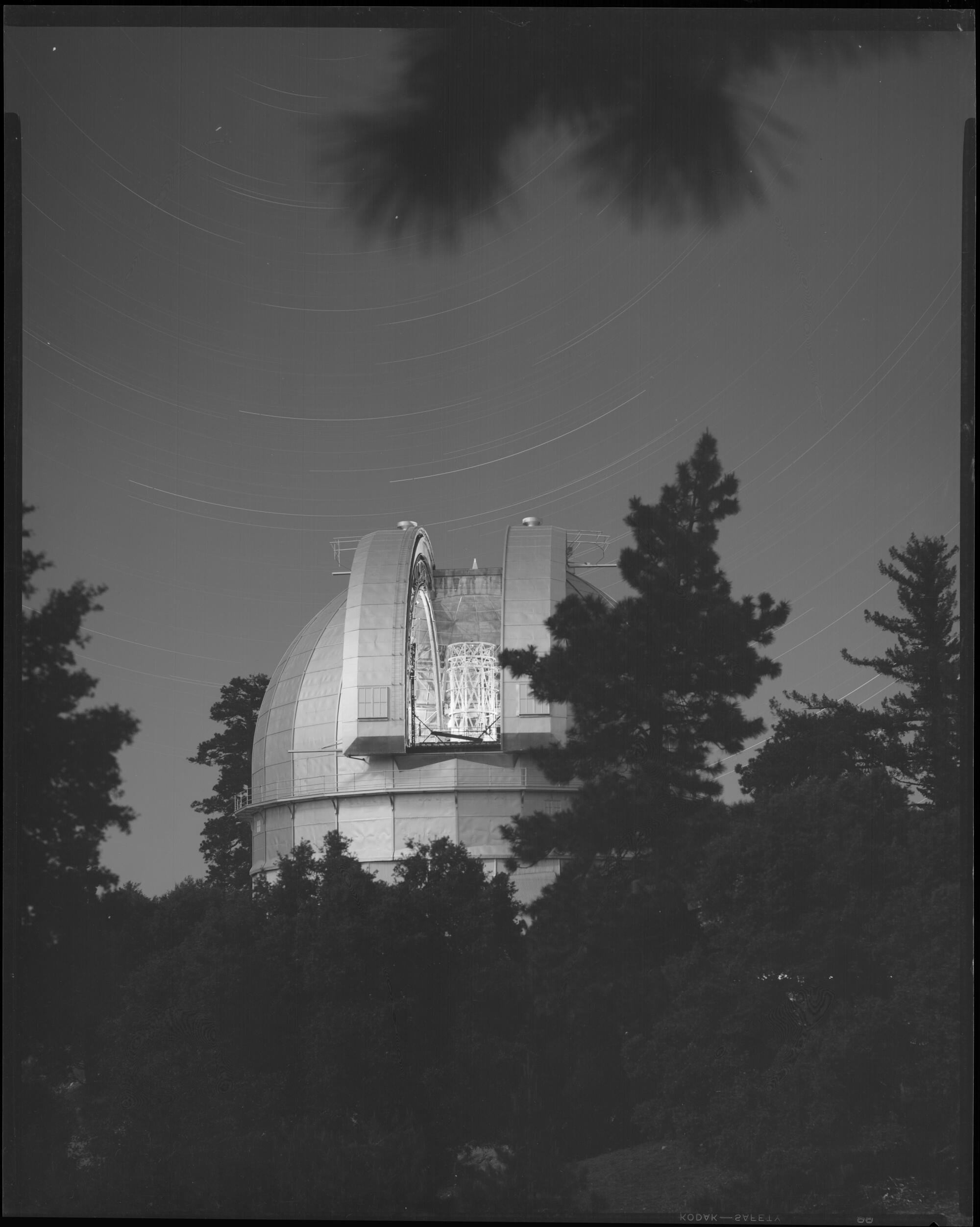 Mt. Wilson Observatory's 100-inch telescope dome by moonlight circa 1950,. Star trails are visible in the sky.