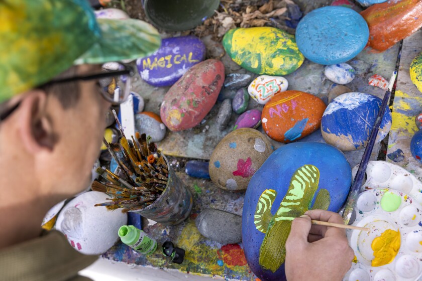 Artist Brian "Pher01" Simmonds paints a cactus on a rock at Dave's Rock Garden in Encinitas on Saturday.