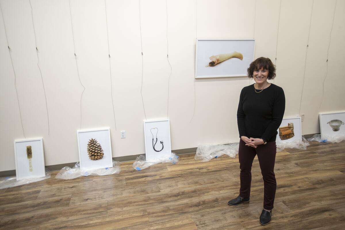 UC Irvine English lecturer Lorene Delany-Ullman shows pieces from "Saved: Objects of the Dead" during setup of the exhibit at UCI on Monday. She and artist Jody Servon joined forces on the exhibit, which includes more than 40 photos and accompanying poetic vignettes of things people kept after their loved ones died.