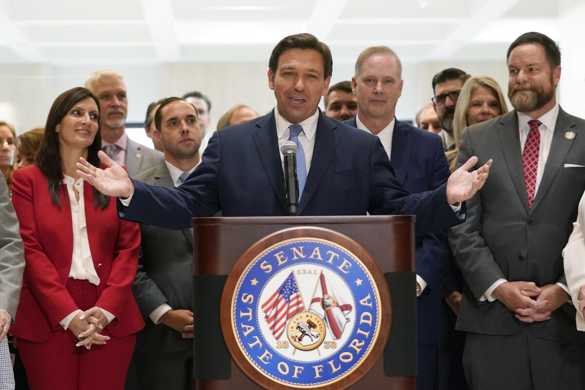 Surrounded by lawmakers, Florida Gov. Ron DeSantis speaks at a lectern