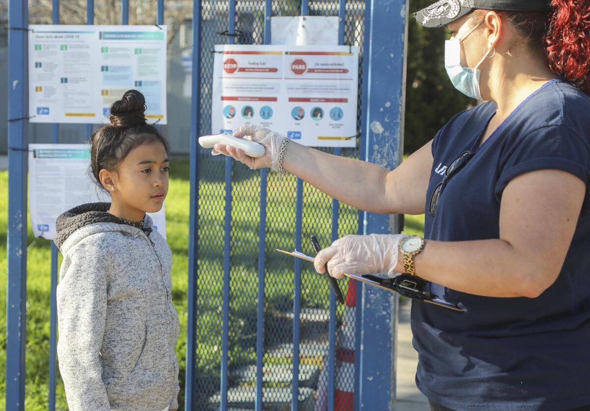 
Natalie Perez takes the temperature of Emily Lucatero, 9, before entering Chase Avenue Elementary School. 