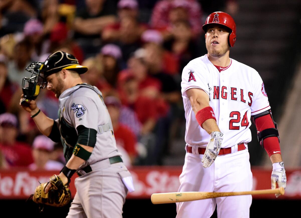 Angels first baseman C.J. Cron (24) tosses his bat in front of Athletics catcher Stephen Vogt after striking out in the seventh inning.